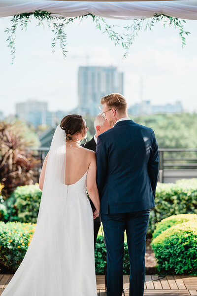 close up back of bride's dress, hands buttoning up bride's dress