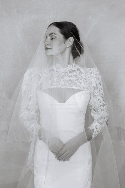 Black and white portrait of a bride with veil over her face