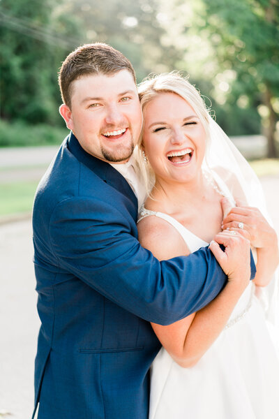 Bride with lace dress and white rose bouquet posing outside in Alabama