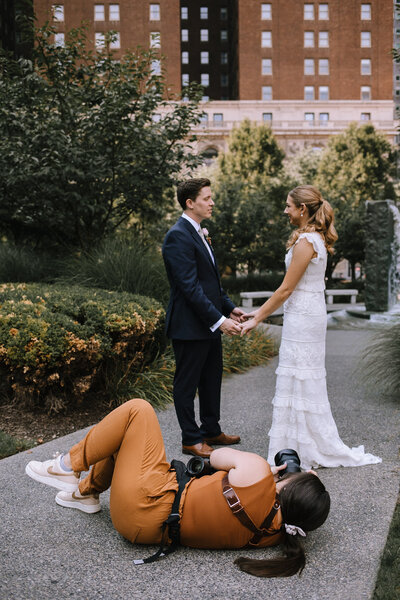 Kaitlin Powell Photography laying on the ground photographing a bride and groom.