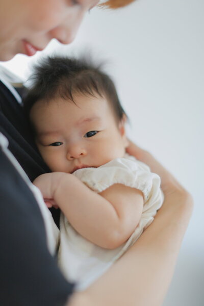 生まれたばかりの赤ちゃんがママに抱っこされて安心している写真