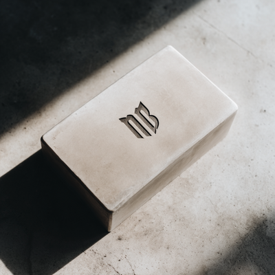 Custom engraved metal brand mark on stone block casting shadow in cinematic lighting, symbolizing identity and reinvention