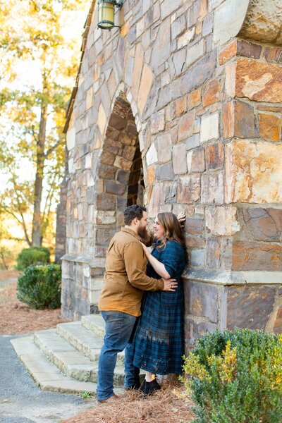engaged couple posing by a stone church