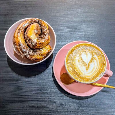 A latte in a pink cup with a pastry at the pause coffee shop in Birmingham