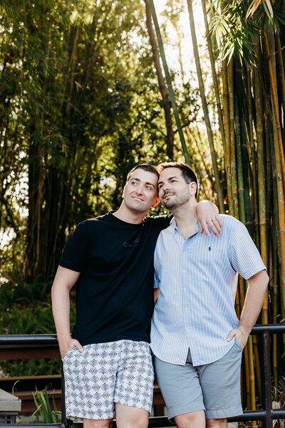 A sweet and peaceful moment as two grooms rest their heads together, embraced under tall bamboo in Disney’s EPCOT Resort area.