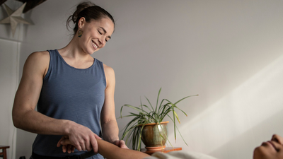 Massage therapist smiling while giving a treatment to a client.