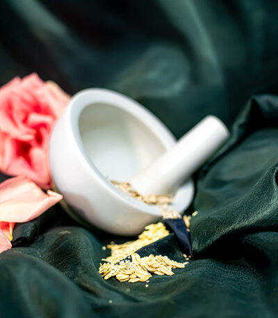 Morter and pestel with dried oatmeal inside laid on a green clothes with dried flowers around