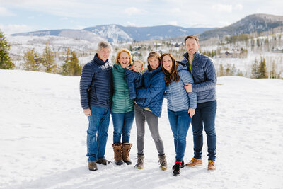 Candid family photos on a snowy winter day with mountain views. Vail's best family photographer.