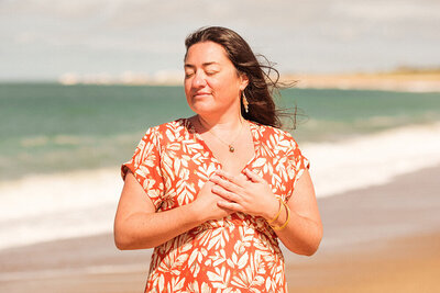 Portrait de natacha, thérapeute énergéticienne à Challans en Vendée, à la plage, mains sur le coeur