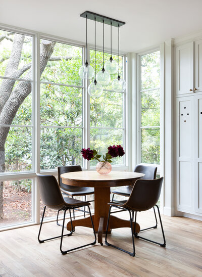 kitchen with big windows.  drop light chandelier. neutral kitchen cabinets with round dining table. big white windows in kitchen. wood floors in kitchen. best interior designer in austin. best interior designer in dripping springs