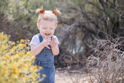 A toddler girl laughing at her hands, captured by las vegas portrait photographer, Jessica Bowles