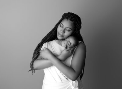 mom  holding newborn baby swaddled in white wrap