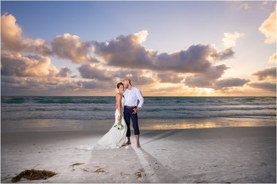 Just married couple posing on the beach at sunset