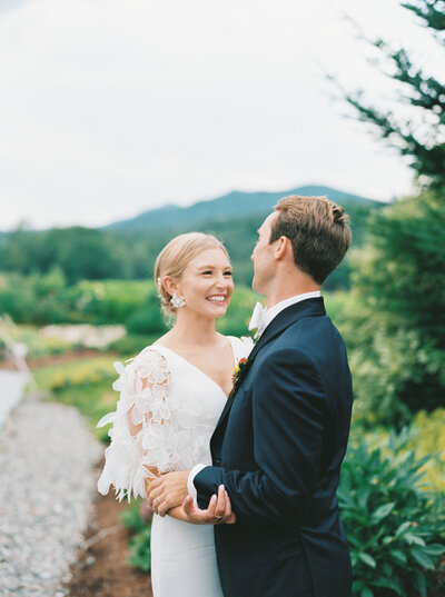Vermont Wedding couple smile big at each other in the gardens of topnotch resort in Stowe.