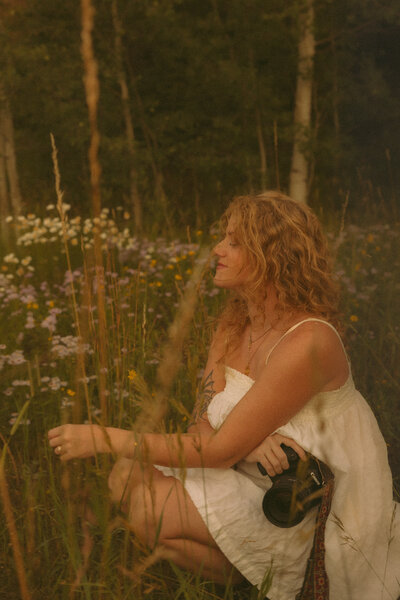 Photographer woman poses in a flower field for portraits in Boulder, Colorado