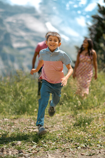 Ein glückliches Kind rennt lachend vor seinen Eltern davon, voller Energie und Entdeckerfreude.