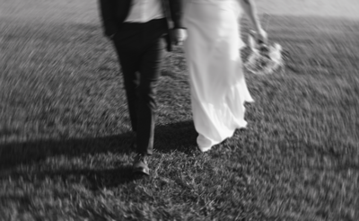 black and white photo of bride and groom walking.