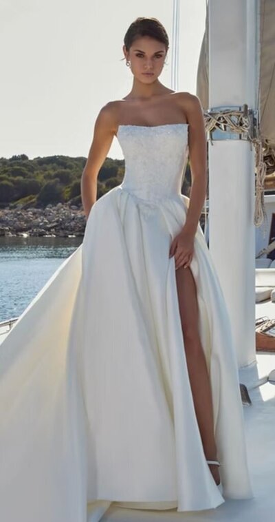 Bride walking gracefully along a sunlit sandy shore wearing a light chiffon oceanfront gown