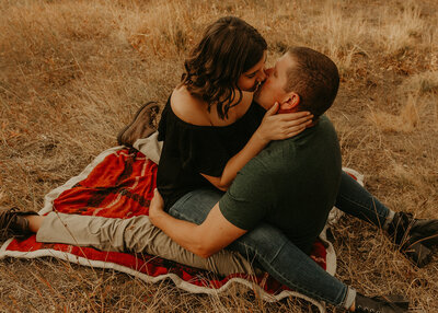 Couple kissing while sitting down on their picnic cloth