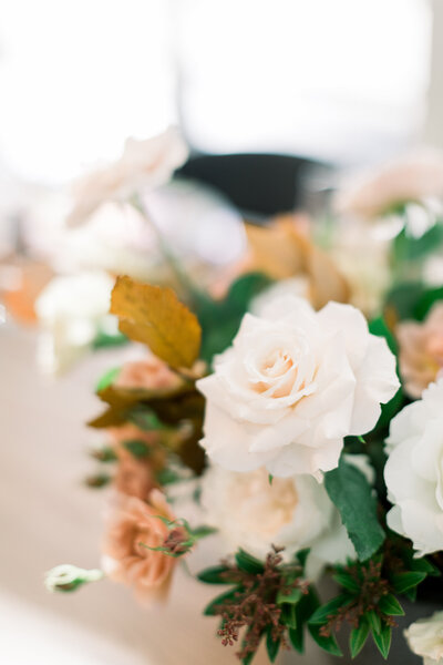 gold vase with white and green flowers and pink background