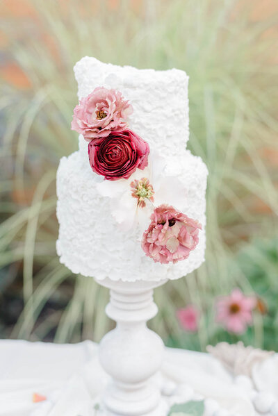 Wedding cake with red and pink flowers by Sierra Elizabeth