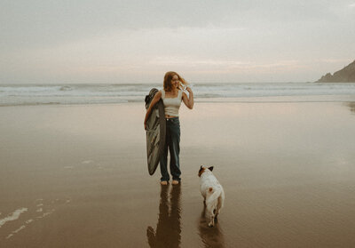 girl standing with her dog on the beach