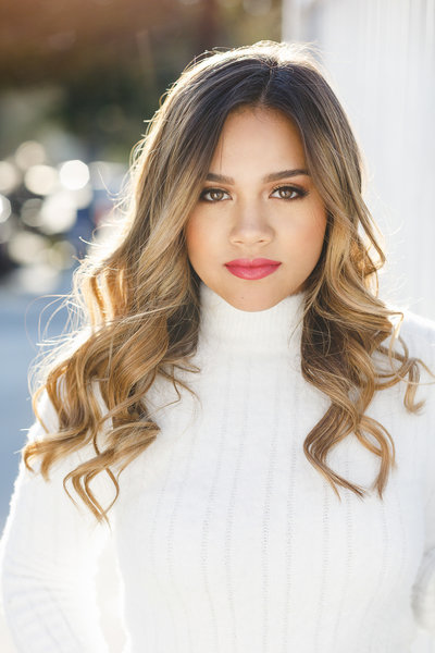  Clean and classic senior headshot featuring a girl with soft curls and flawless makeup in a cozy white turtleneck sweater. Bright natural light gives this a polished and timeless feel.