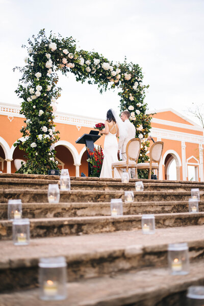 bride and groom standing under flower arche