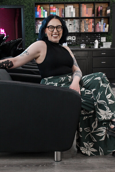 A girl with glasses sitting in a  shampoo chair at a salon