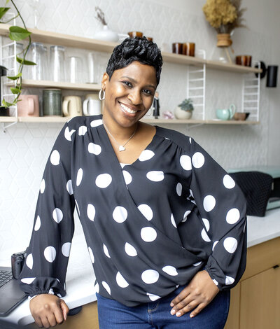 Metro Detroit  Senior Photographer with short pixie haircut in black polka dot blouse and blue jean jeggings posing casually