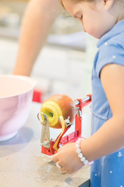Apple being peeled for homemade applesauce by toddler