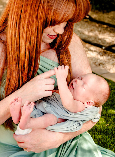 Stunning red head mom playing with newborn's hands at her Arizona home during in-home newborn session