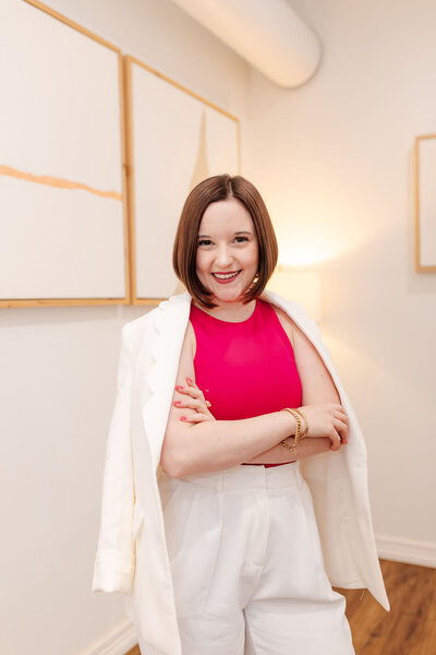 Woman with short brown hair wearing bright pink blazer smiling at camera
