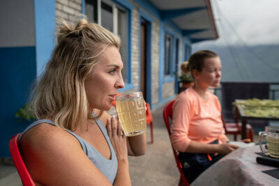 A woman with short blonde hair sips honey lemon ginger tea in Nepal.