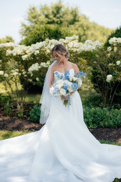 bride with her bridal bouquet looking down at her wedding dress