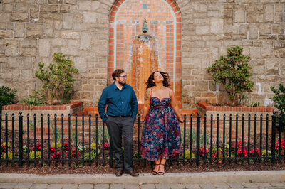 A couple poses in front of a fence