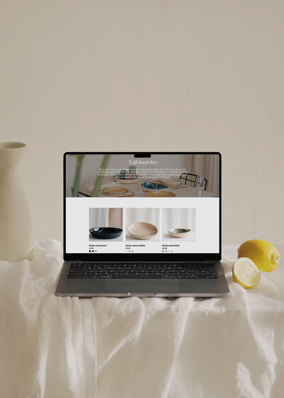 Laptop met webshop van Bord aan Tafel, met serviescollectie en citroenen als frisse styling op wit linnen
