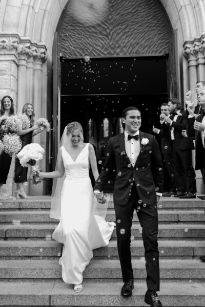 Bride and groom joyfully walk down the church steps after their wedding