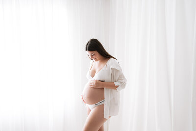 A pregnant women holding her bump at a Horsham newborn photoshoot