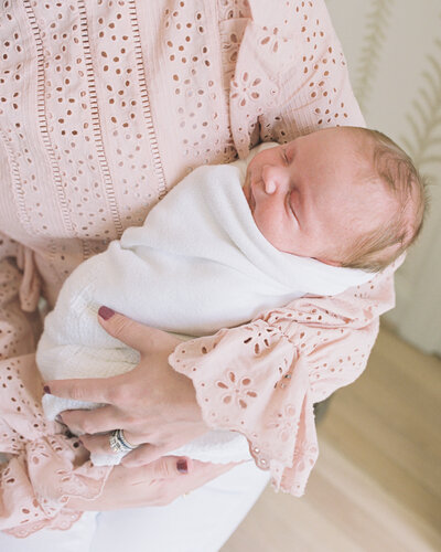 Newborn photography while being held by mom