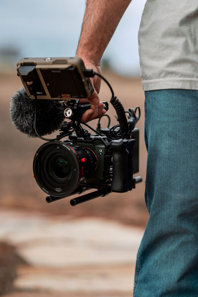 Close-up of Joseph Mayden holding a professional cinema camera rig with external monitor and microphone, used for high-quality videography and storytelling.