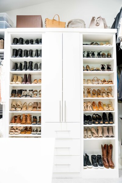 A bedroom closet featuring rows of organized shoes