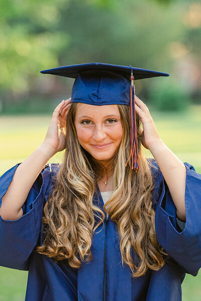 cap and gown photo of a senior adjusting her cap