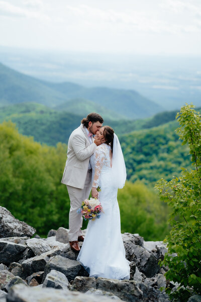 photo of bride and groom standing on a rock cliff kissing taken by montana wedding photographer