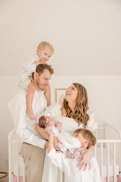 Toddler on his dad shoulders while mom looks up at him holding her newborn. -Newborn Photographer Greenville