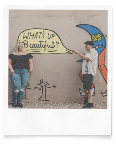 couple poses next to mural for engagement photo session in las vegas