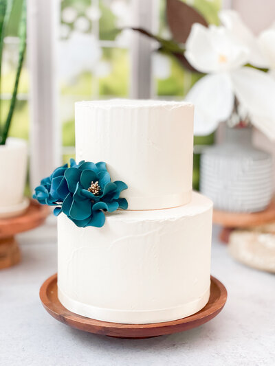 Two tier cake displaying a  Sugar flower bundle of Hand painted gold Open roses