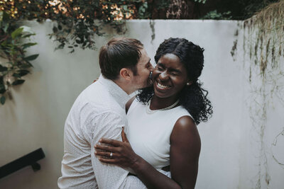 A husband kisses his wife on the cheek as she laughs during their portrait session in Memphis.