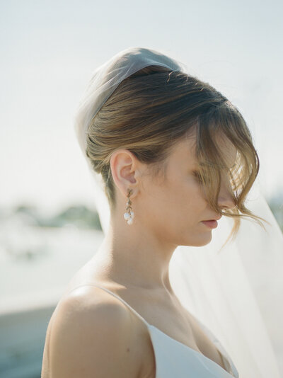 candid film wedding photography in Northern Michigan, bride with wind in hair, pearl wedding earrings in luminous light