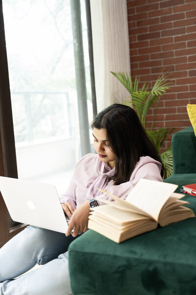 image of Maria John sitting on a sofa while holding a laptop